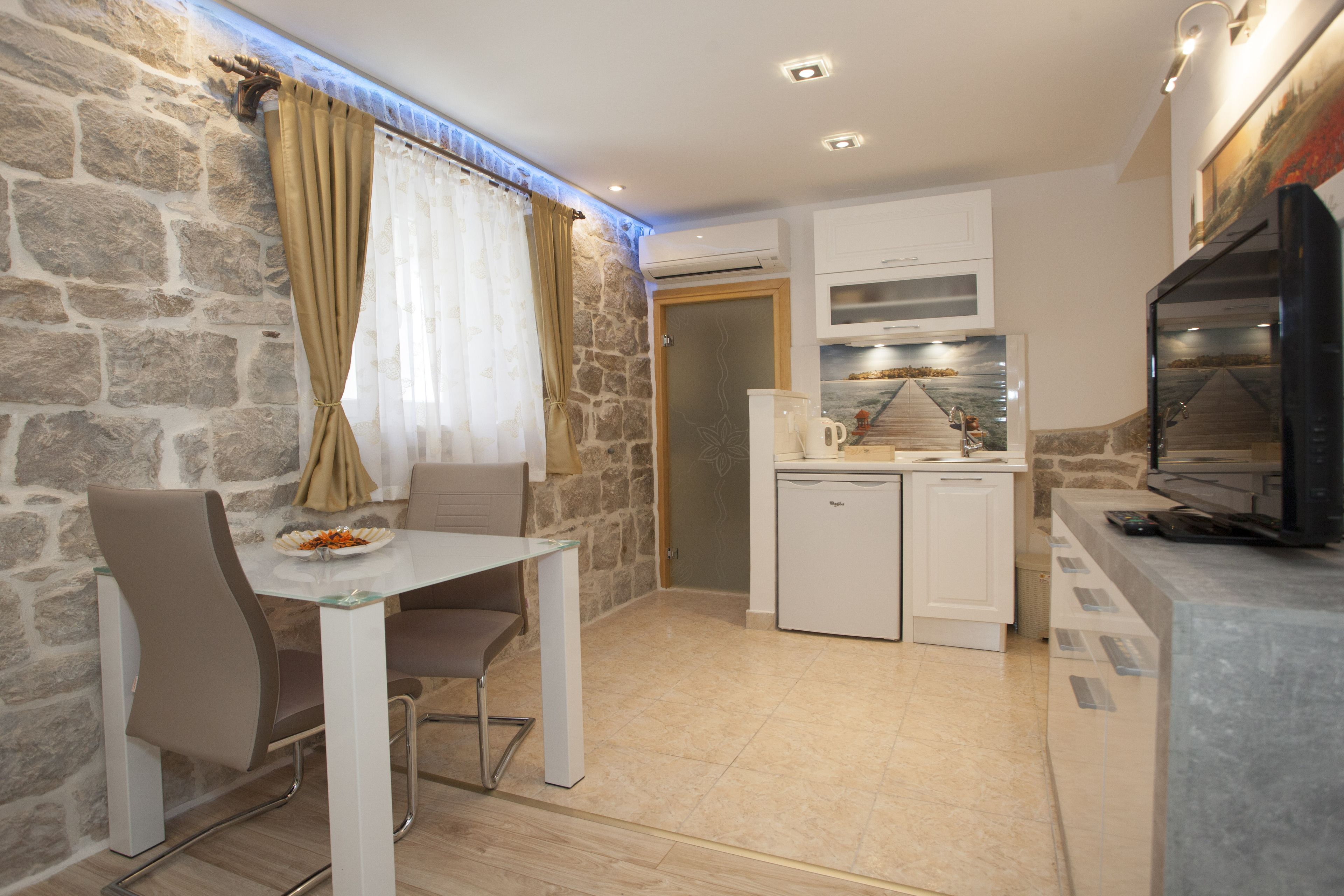 A compact kitchen with a dining area, stone walls, and modern appliances.