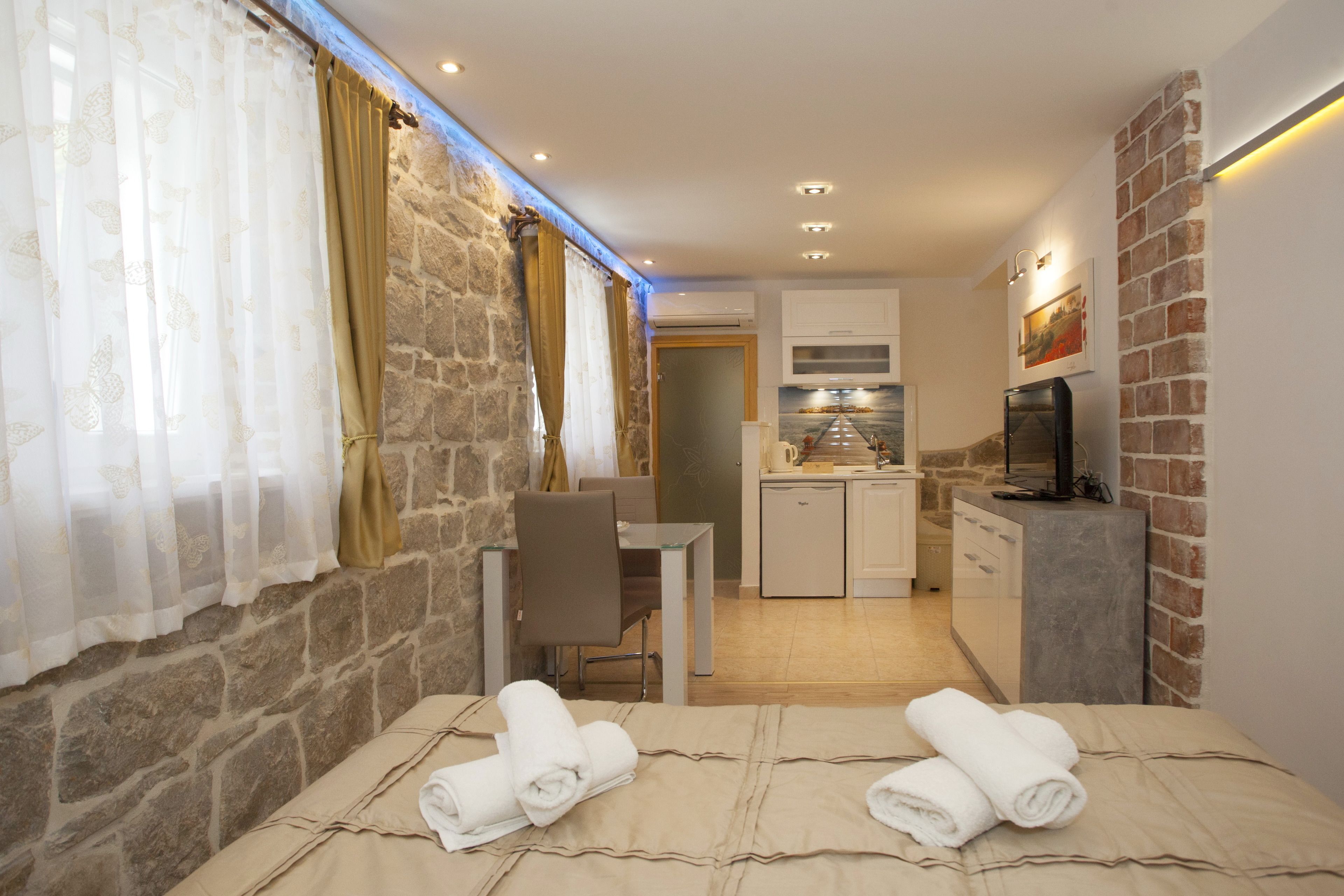 Une chambre d’hôtel de taille réduite, comprenant un lit, une petite table, une chaise, un coin cuisine et un téléviseur.