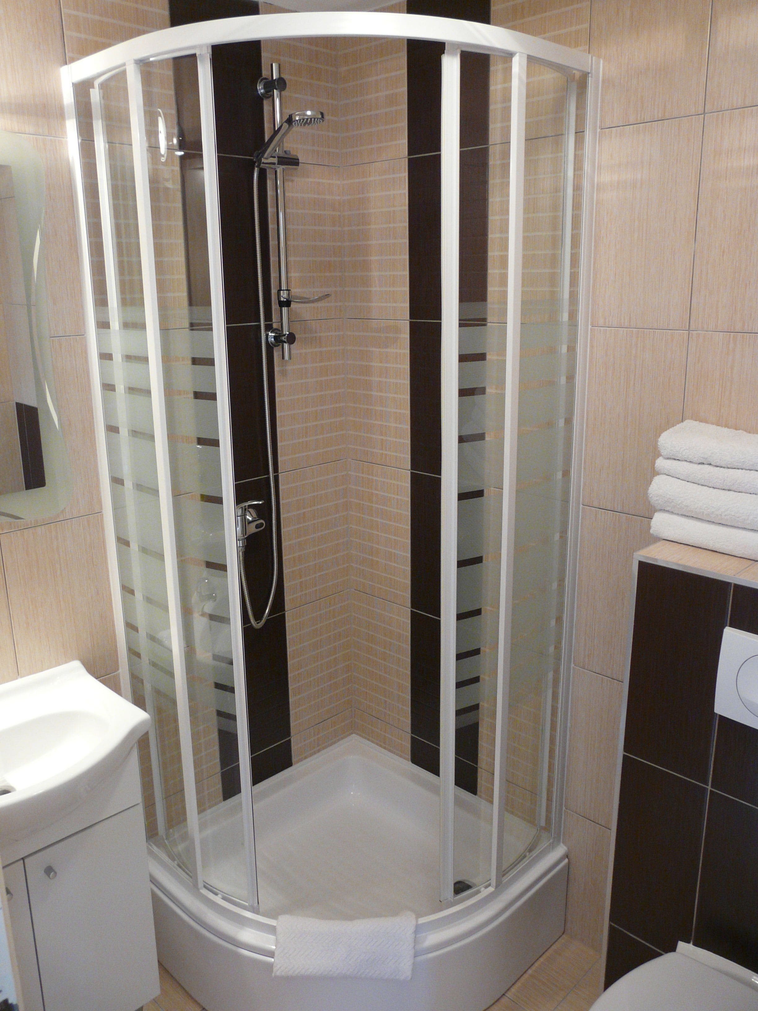 A glass-enclosed shower stall with a white sink and a towel rack.