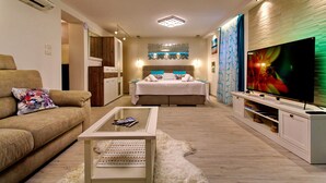 A modern living room with a sofa, a coffee table, a TV, and a bed with a headboard. - House Sandra (Split)