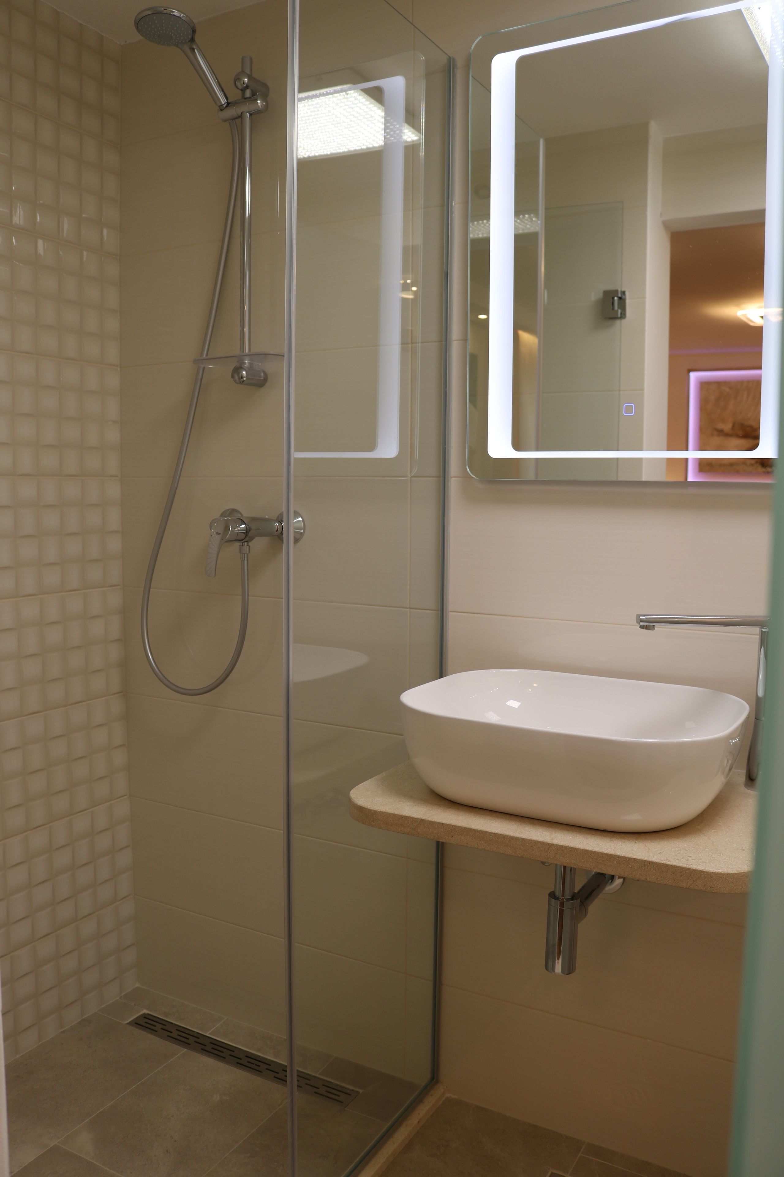 A modern bathroom with a glass-enclosed shower, a white sink, and a mirror above the sink.