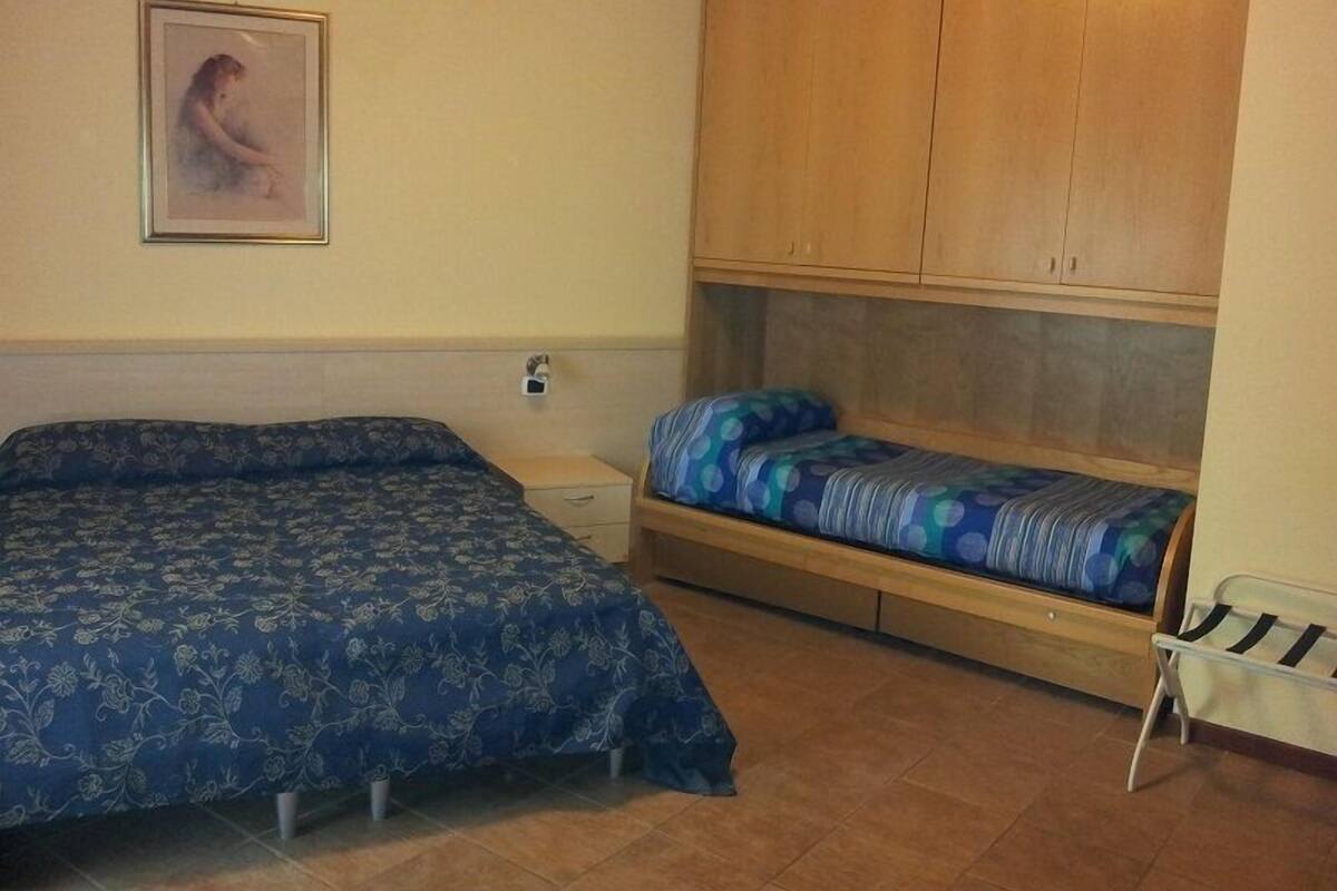 Un dormitorio con cama, mesita de noche, armario y una pequeña mesa.
