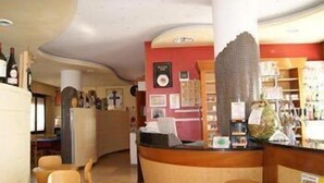 A bar area with a curved counter, chairs, and a variety of bottles and glasses.