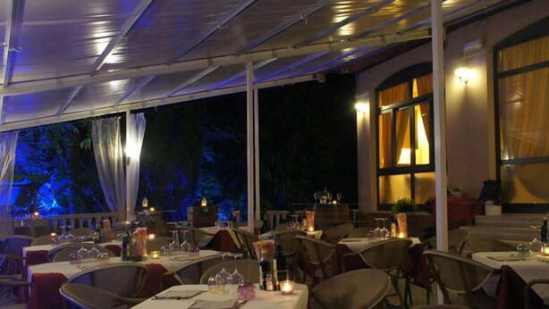 An outdoor dining area with tables set for a meal, surrounded by chairs and covered by a canopy.