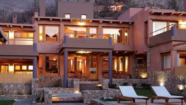 Un edificio moderno de varios pisos con fachada de piedra, ventanas amplias y terraza.