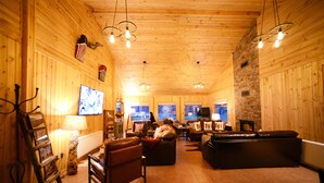 Una habitación acogedora con paneles de madera, una chimenea, asientos de cuero y un televisor.