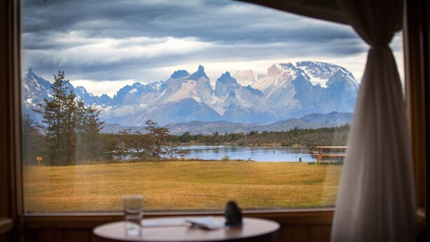 Una habitación con vistas a montañas y a un lago, visibles a través de una ventana.