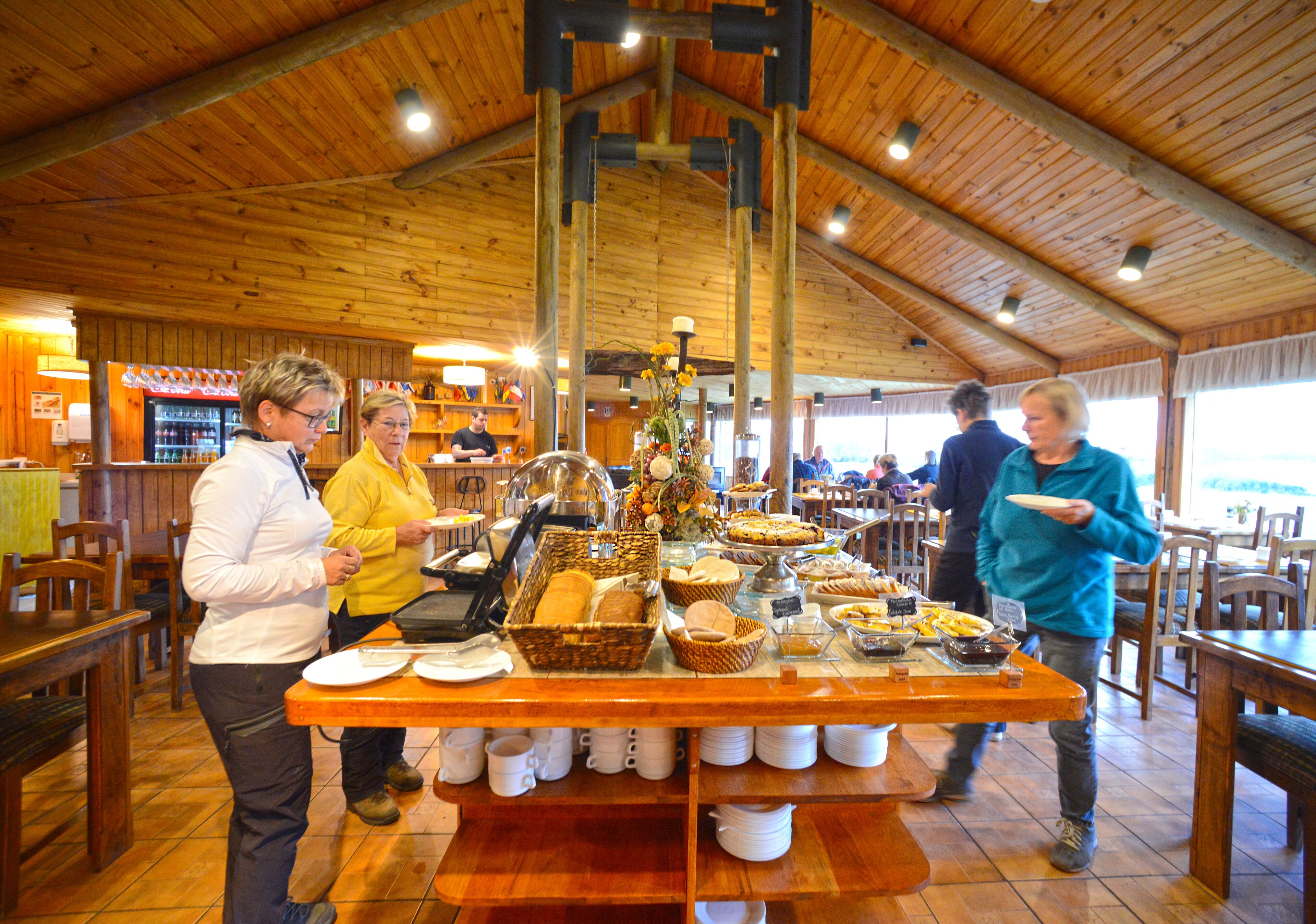 A buffet setup with various food items and a coffee station in a wooden interior setting.