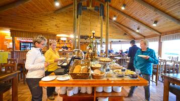 A buffet setup with various food items and a coffee station in a wooden interior setting.