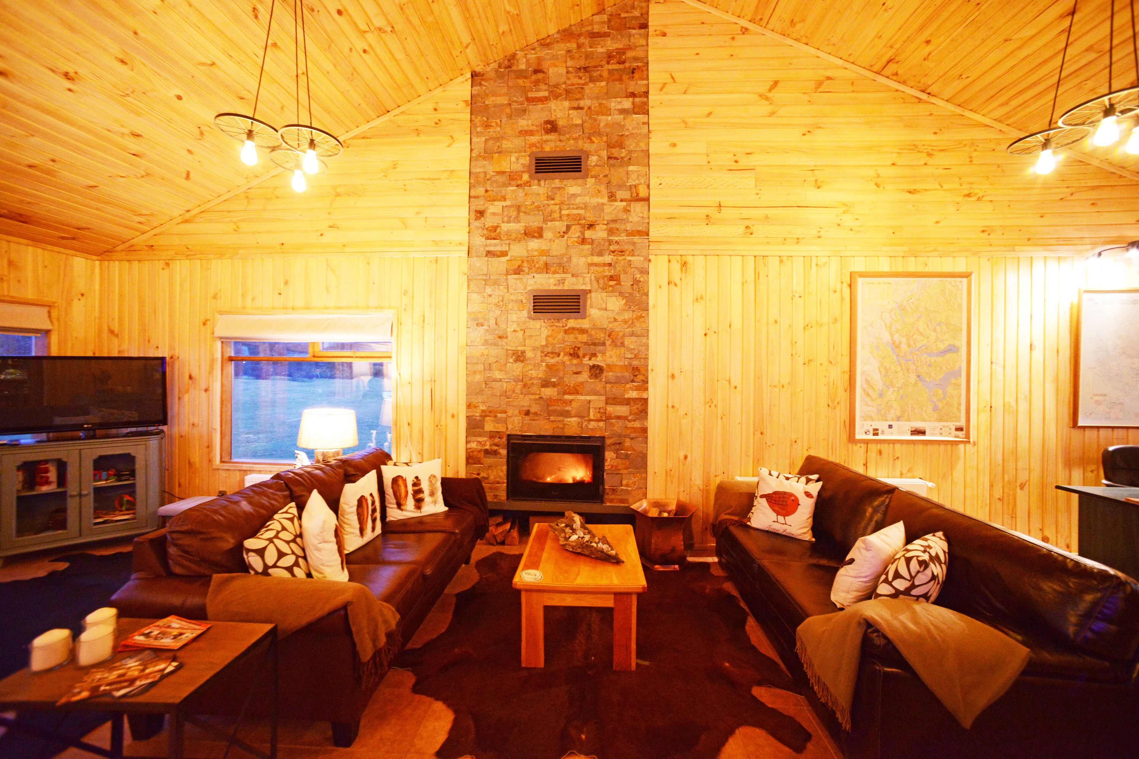 A cozy living room with a fireplace, leather sofas, a wooden coffee table, and a television.