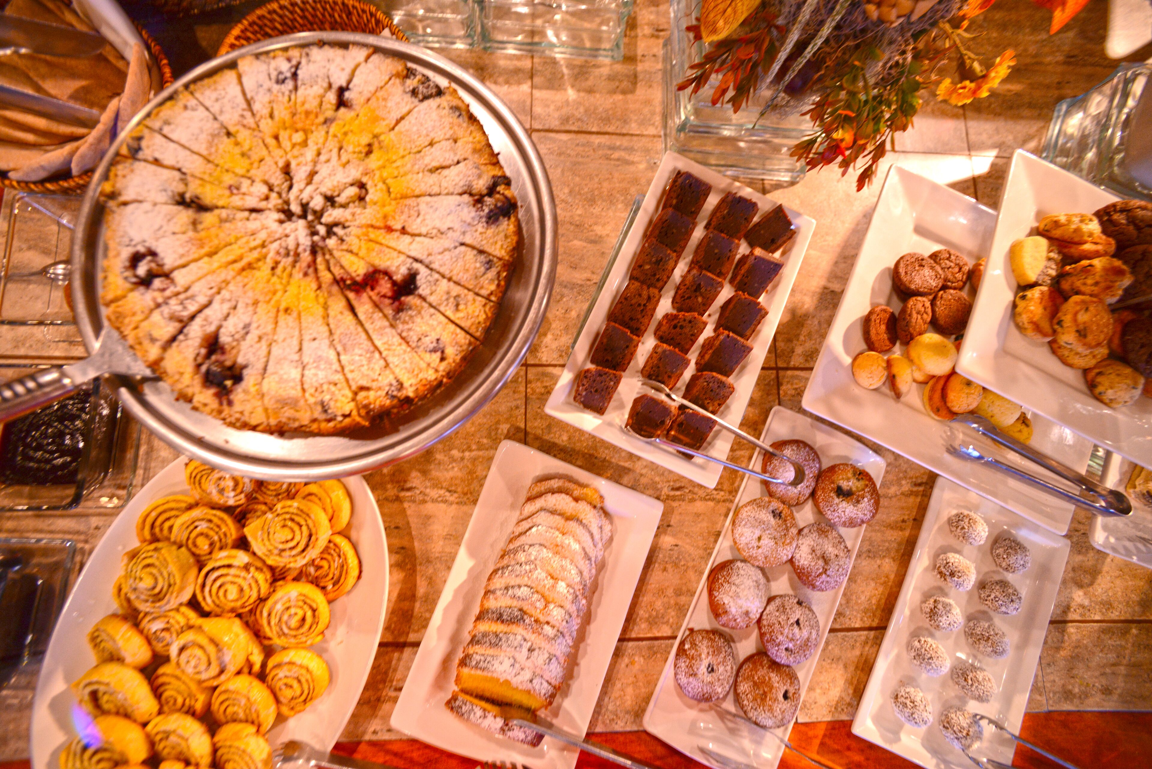 A buffet table with various desserts including a large cake, pastries, and other sweet treats.