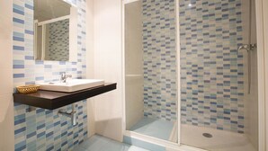 A bathroom with a shower, a sink with a black countertop, and a mirror. - Hostal Casa Salvador (Granada)