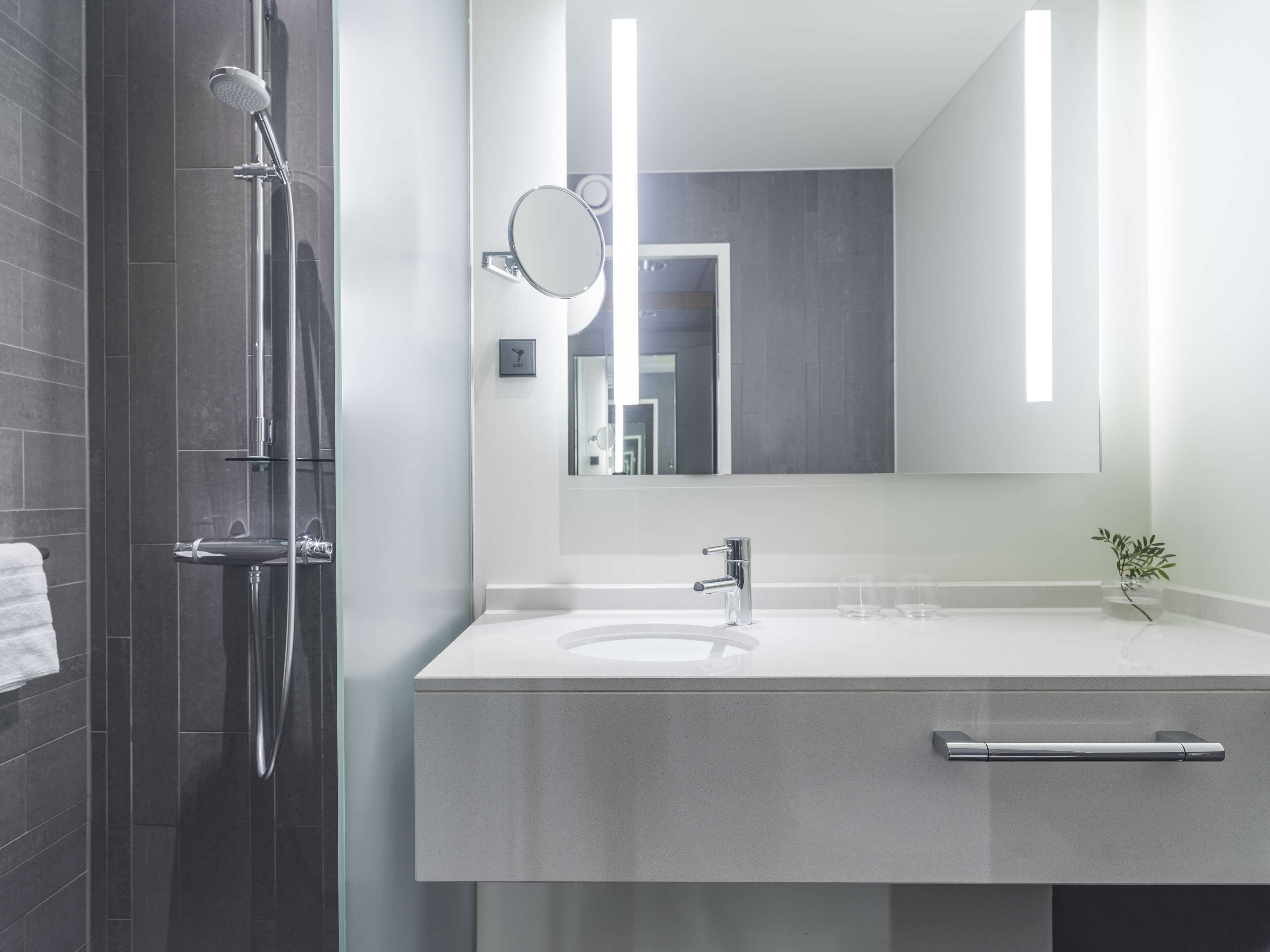 Ein modernes Badezimmer mit Dusche, Waschbecken und Spiegel.
