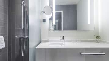 Ein modernes Badezimmer mit Dusche, Waschbecken und Spiegel.