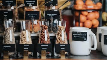 A display of various nuts and dried fruits in glass containers with labels, and a mug of yogurt.