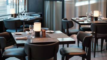 Un restaurante moderno con mesas y sillas de madera oscura, cuidadosamente dispuestas con platos, vasos y cubiertos.
