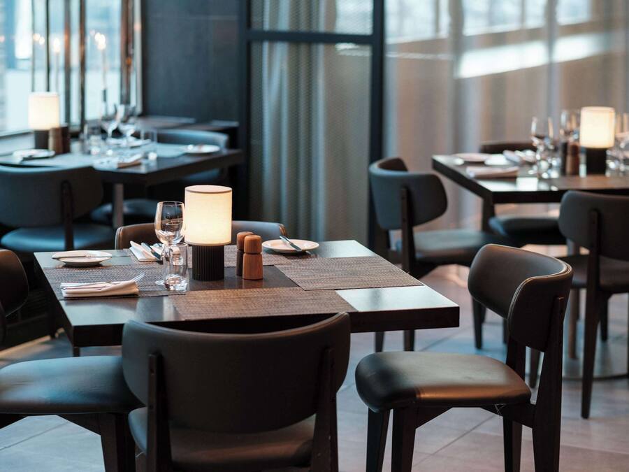 Un restaurante moderno con mesas y sillas de madera oscura, cuidadosamente dispuestas con platos, vasos y cubiertos.