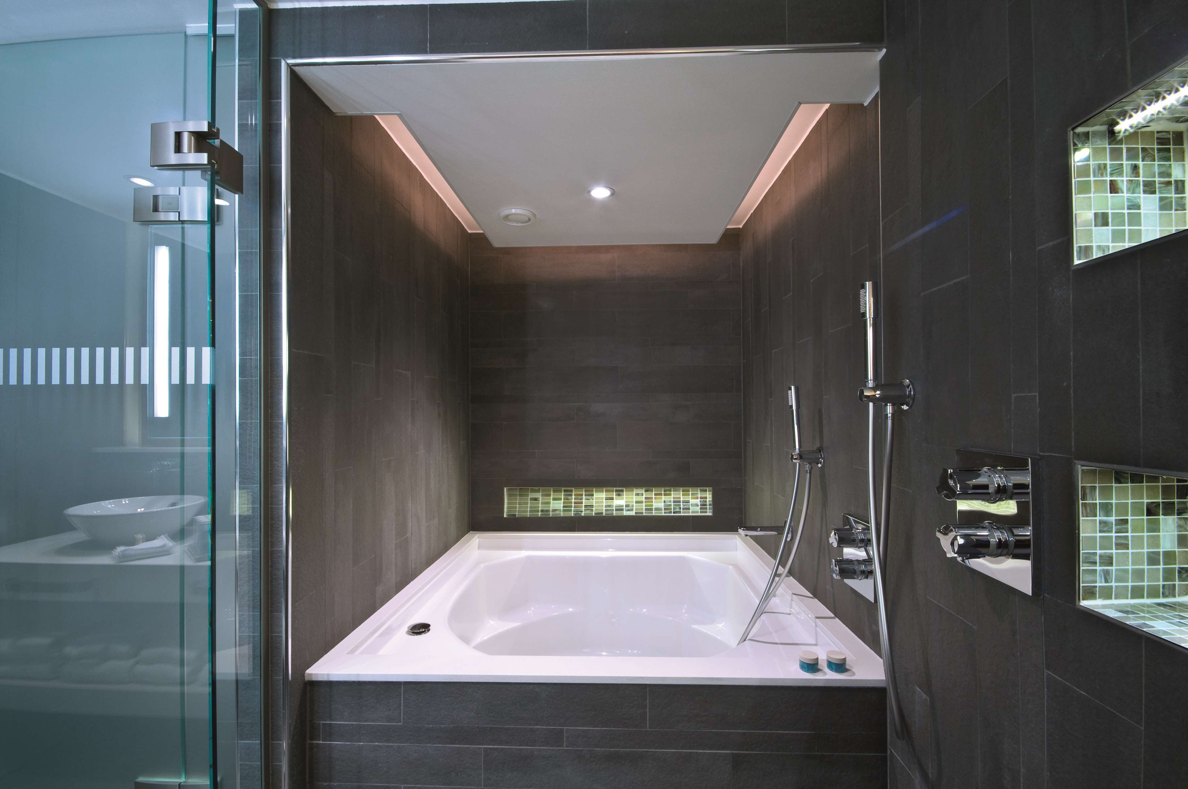 A modern bathroom with a freestanding bathtub, a glass shower enclosure, and a tiled backsplash.