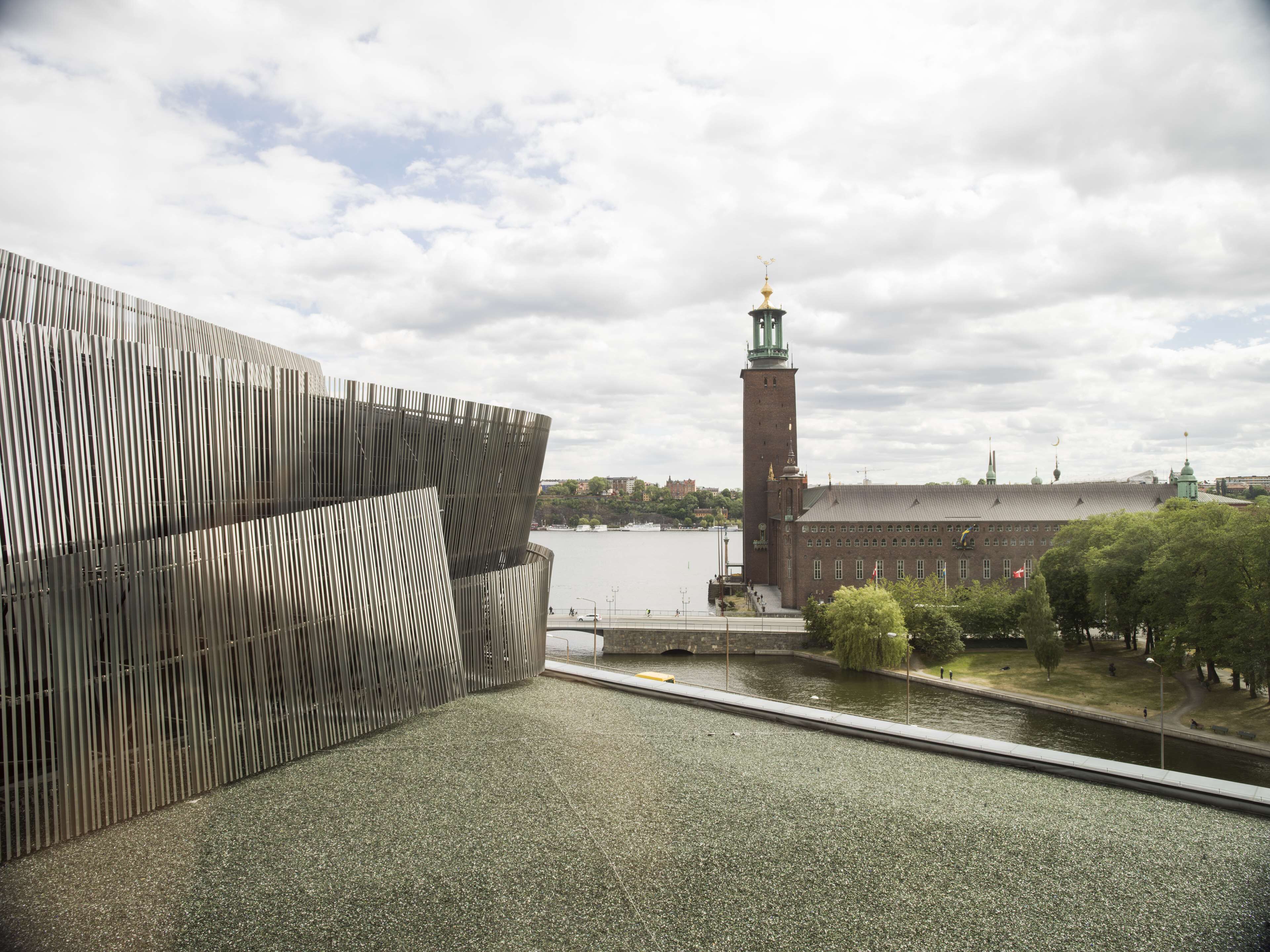 Een modern gebouw met een reflecterende gevel, een historische toren met een klok en een rivier op de achtergrond.