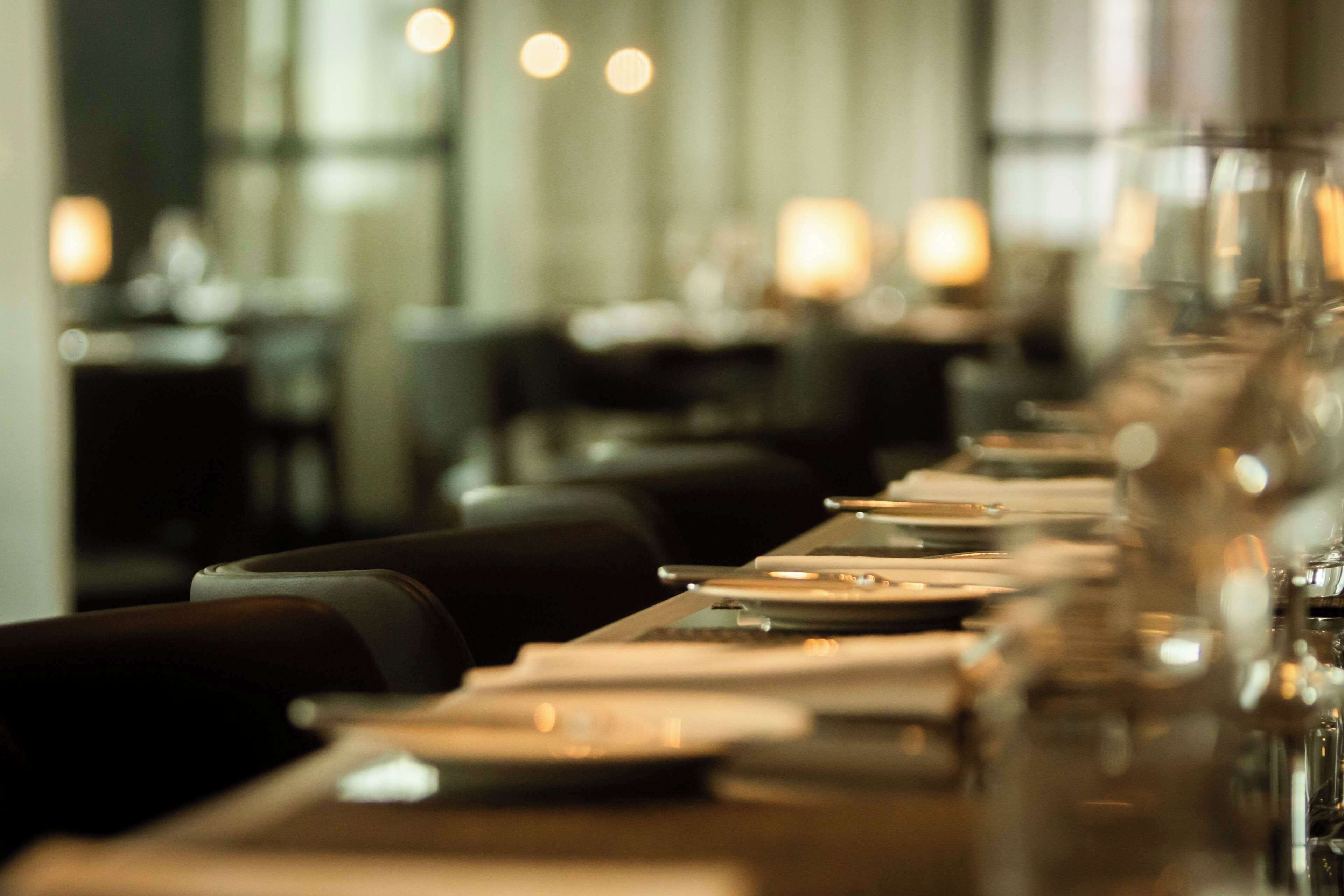 Un restaurante con una larga mesa dispuesta para comer, sillas y velas.