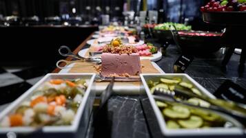 Un bufé con diversos alimentos, incluyendo un pastel con cereza en la cima.