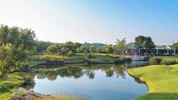 A serene landscape with a pond, green grass, and trees.