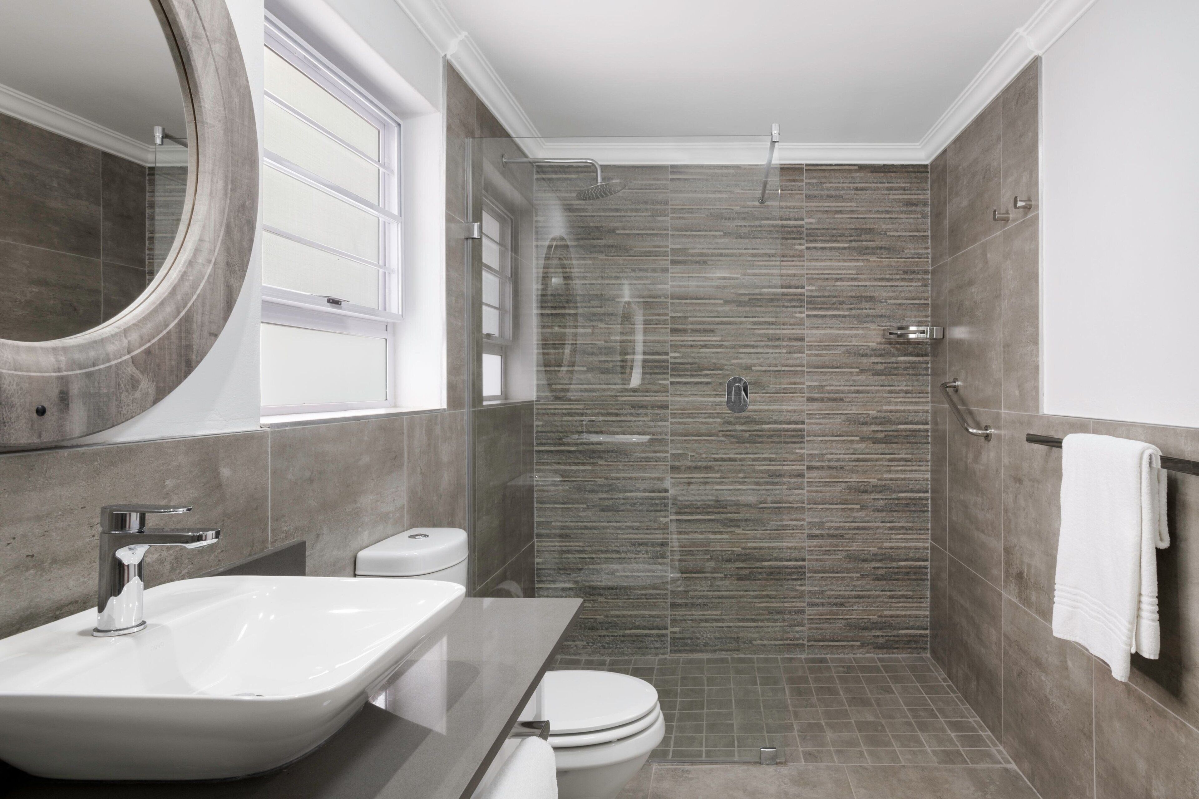 A modern bathroom with a large sink, toilet, and walk-in shower.