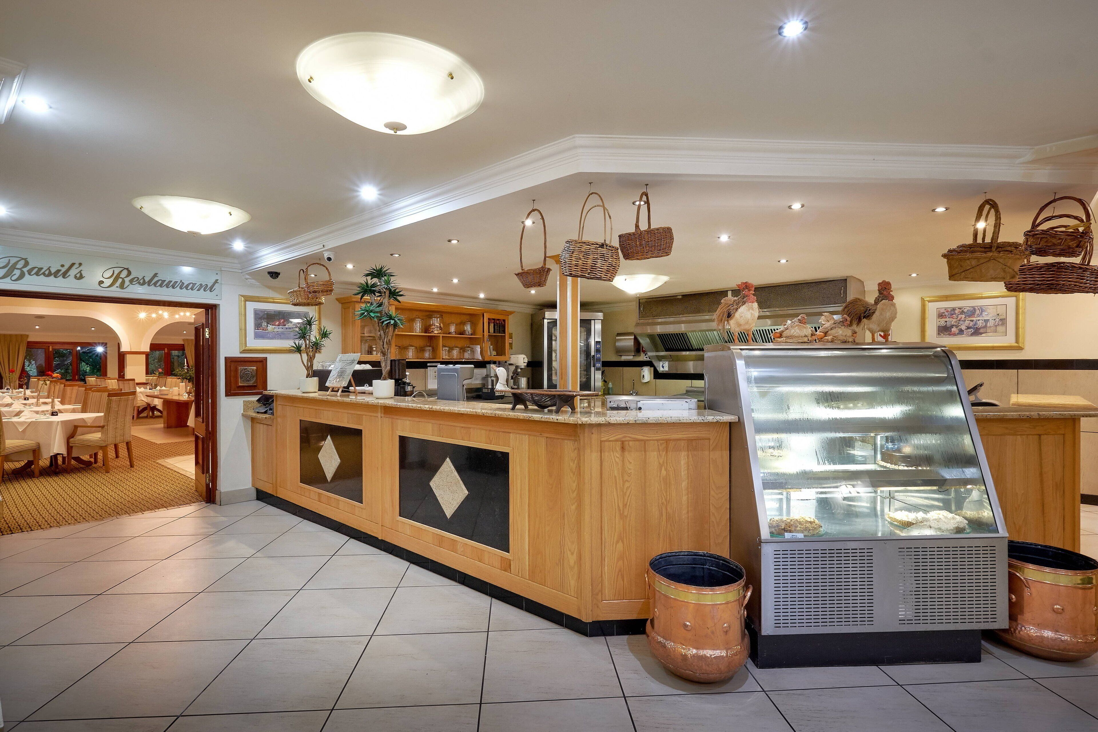 A restaurant interior with a wooden counter, hanging baskets, and a display case.