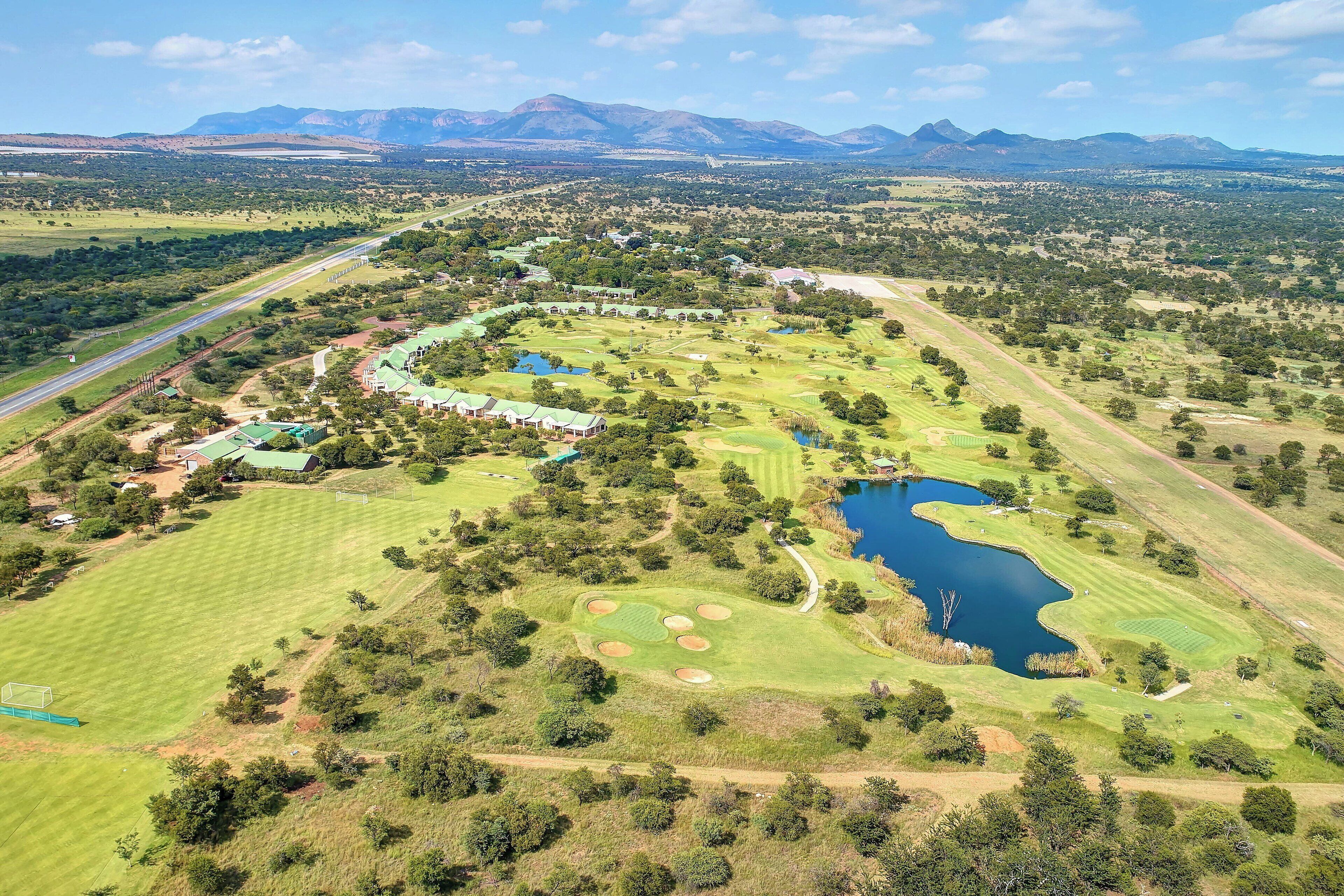Vue aérienne d’un parcours de golf comportant de nombreux bunkers, des obstacles d’eau et un club-house.