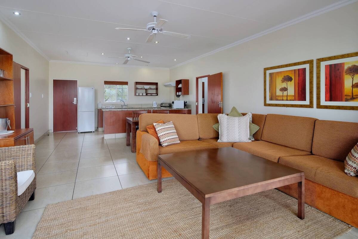 A spacious living area with a sofa, coffee table, and a kitchen in the background.