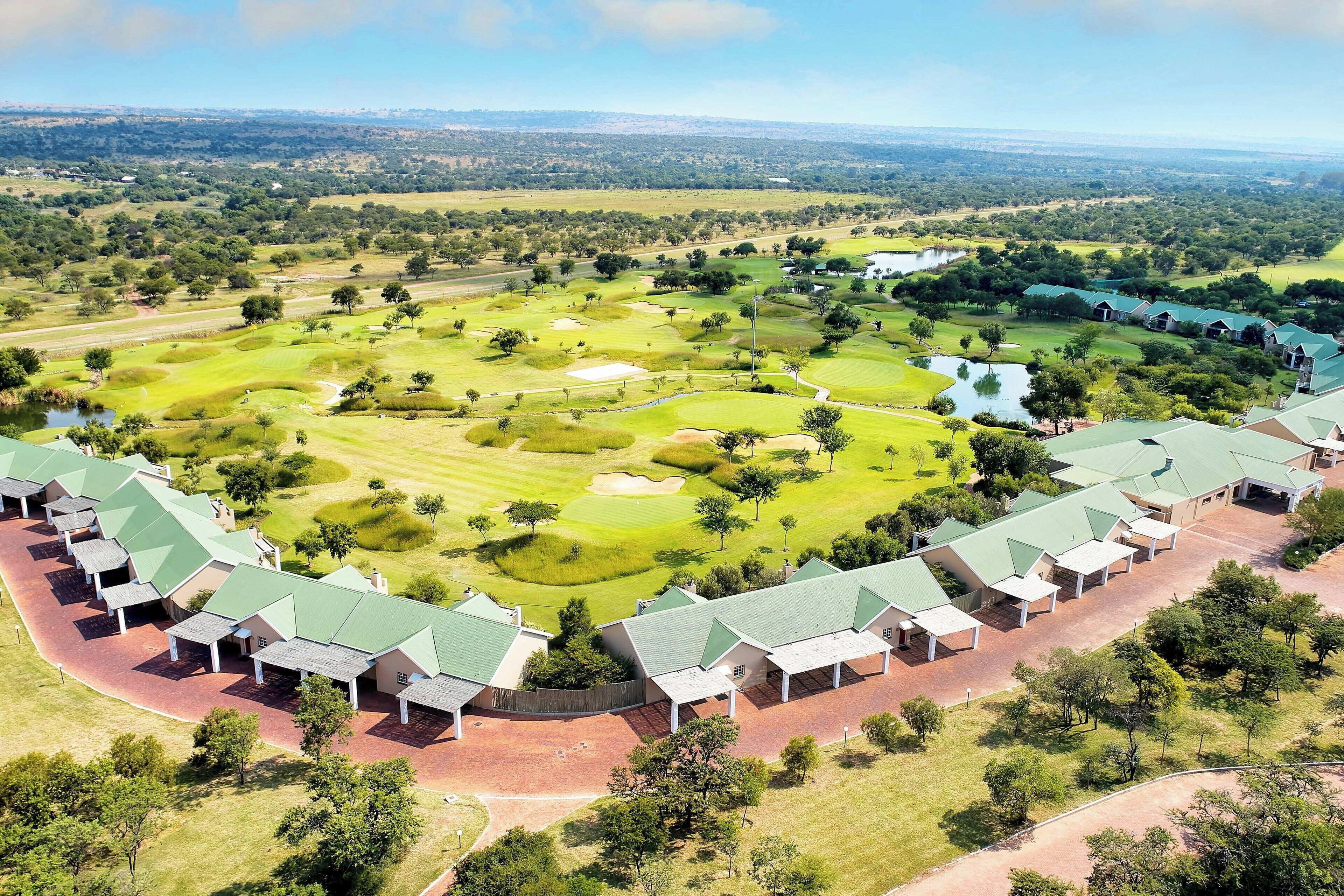 Vista aérea de un campo de golf con una hilera de edificios con techos verdes.