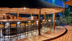 A covered outdoor bar area with a thatched roof, bar stools, and a central bar counter. - Protea Hotel by Marriott Polokwane Ranch Resort (Polokwane)