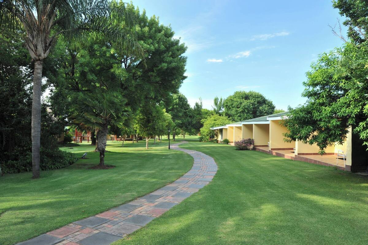 A well-maintained lawn with a curved stone pathway leading to a building with a yellow facade.