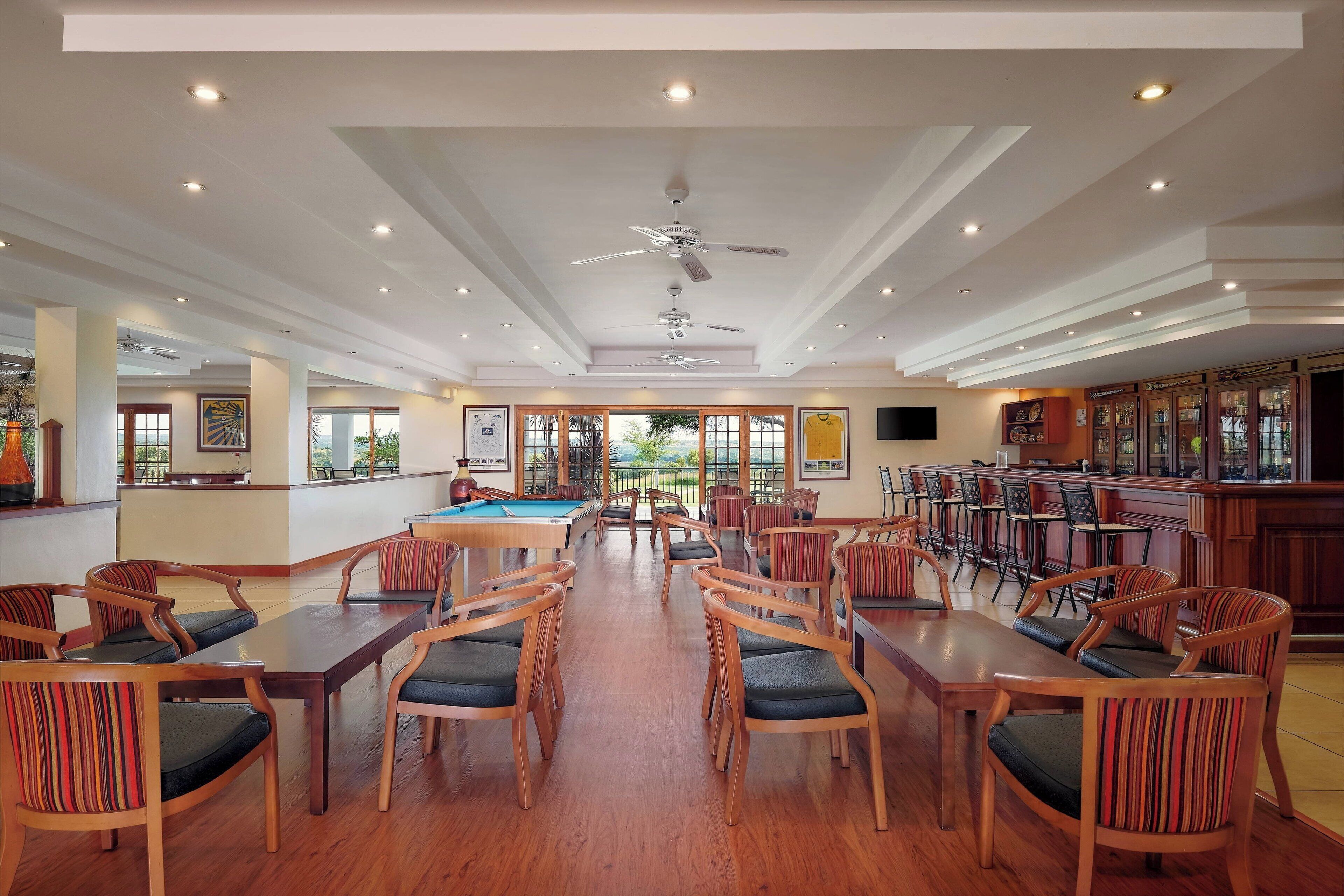 A spacious indoor area with wooden tables and chairs, a pool table, and a bar area.