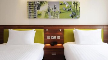 Habitación de hotel con dos camas, cabecero de madera, mesita de noche con teléfono y una obra de arte colgada en la pared.