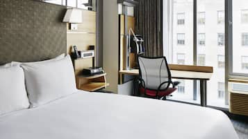 Una habitación de hotel con una cama grande, un escritorio con silla, una lámpara y un teléfono.