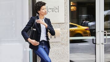 A woman leaning against a building with a sign that reads "The Jewels."