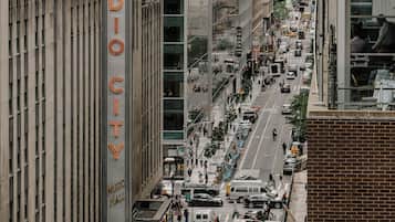 Una calle urbana concurrida con edificios, incluyendo un llamativo letrero de 'Radio City Music Hall'.