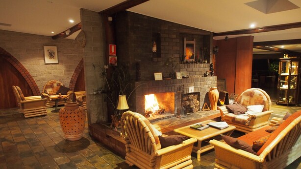 Un rincón tranquilo con mobiliario de mimbre, chimenea y suelo de baldosas de piedra.