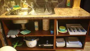 Una cocina con encimera de granito, un lavamanos, un escurreplatos, una estufa y diversos utensilios de cocina.