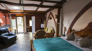 Una habitación acogedora con una cama, un sillón de cuero, una mesa de madera y una mesita con una lámpara.