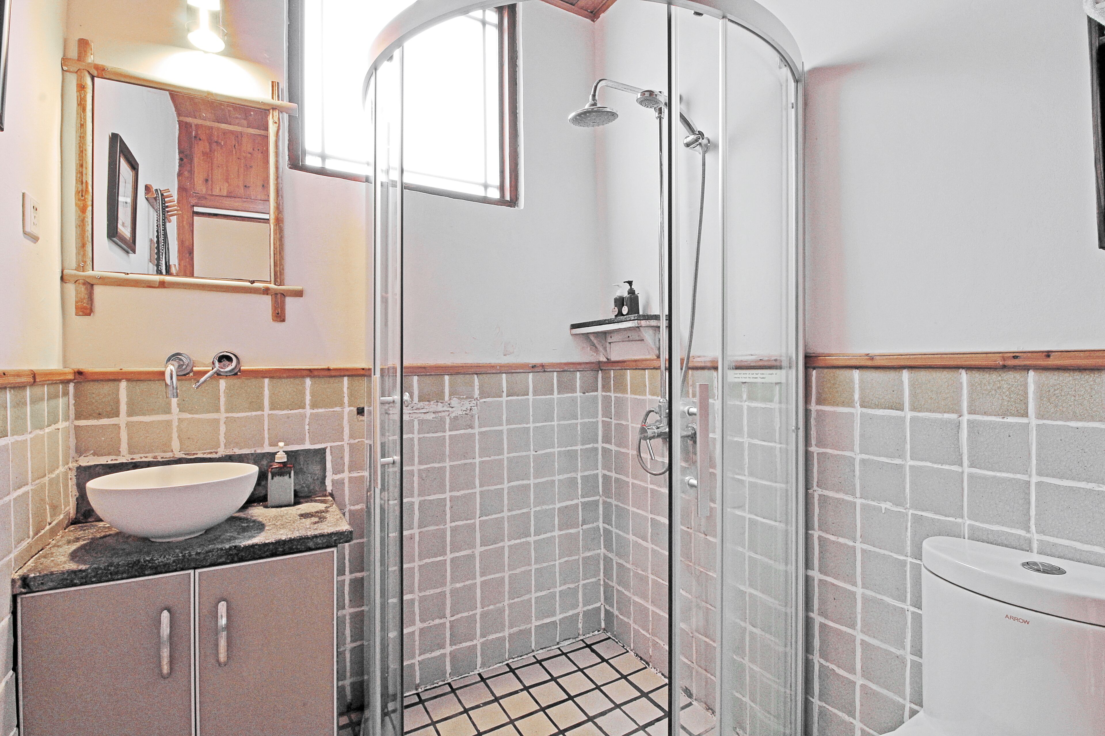 A bathroom with a white sink, a mirror, a shower enclosure, and a toilet.