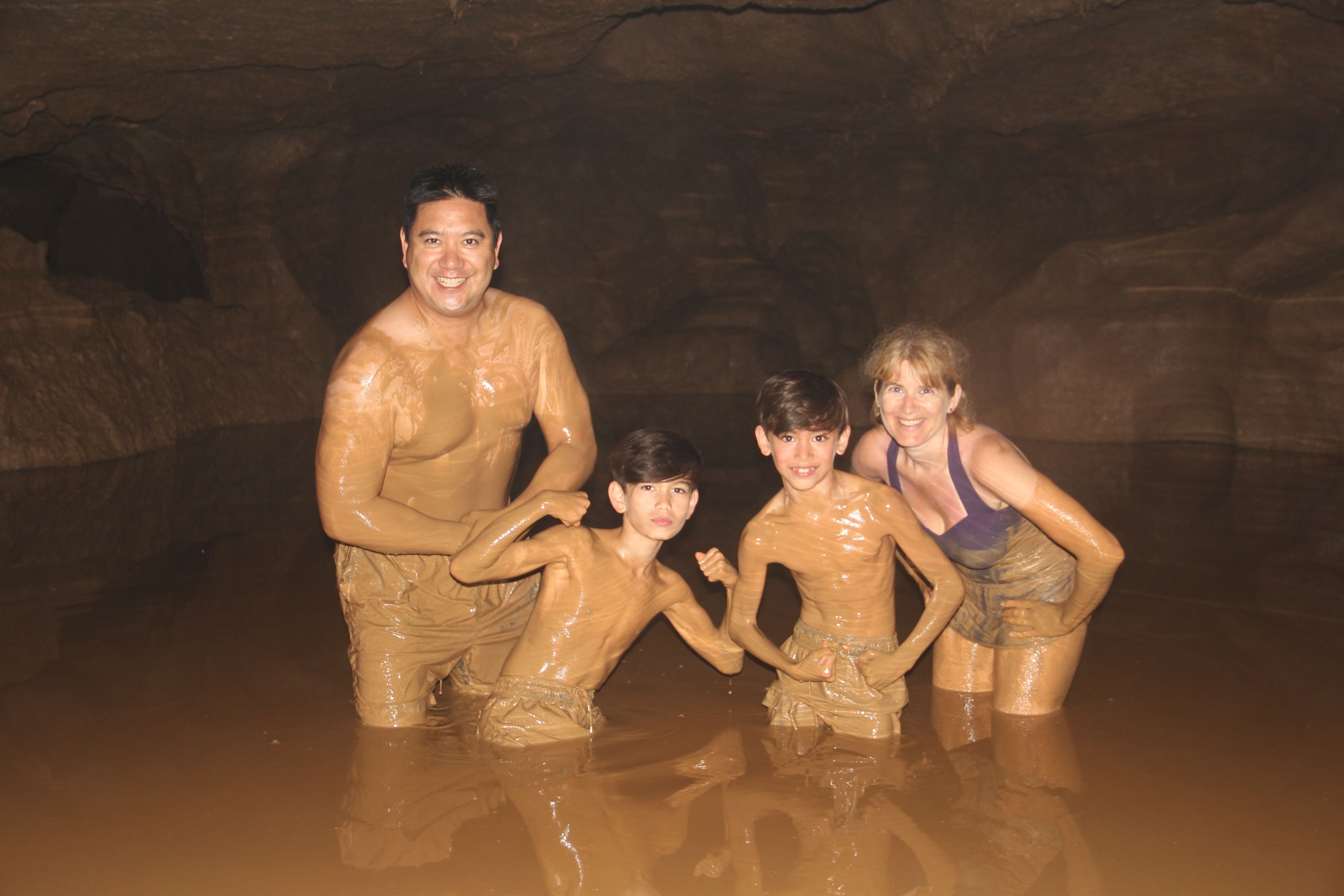 A group of people in a cave-like setting with a rocky background.