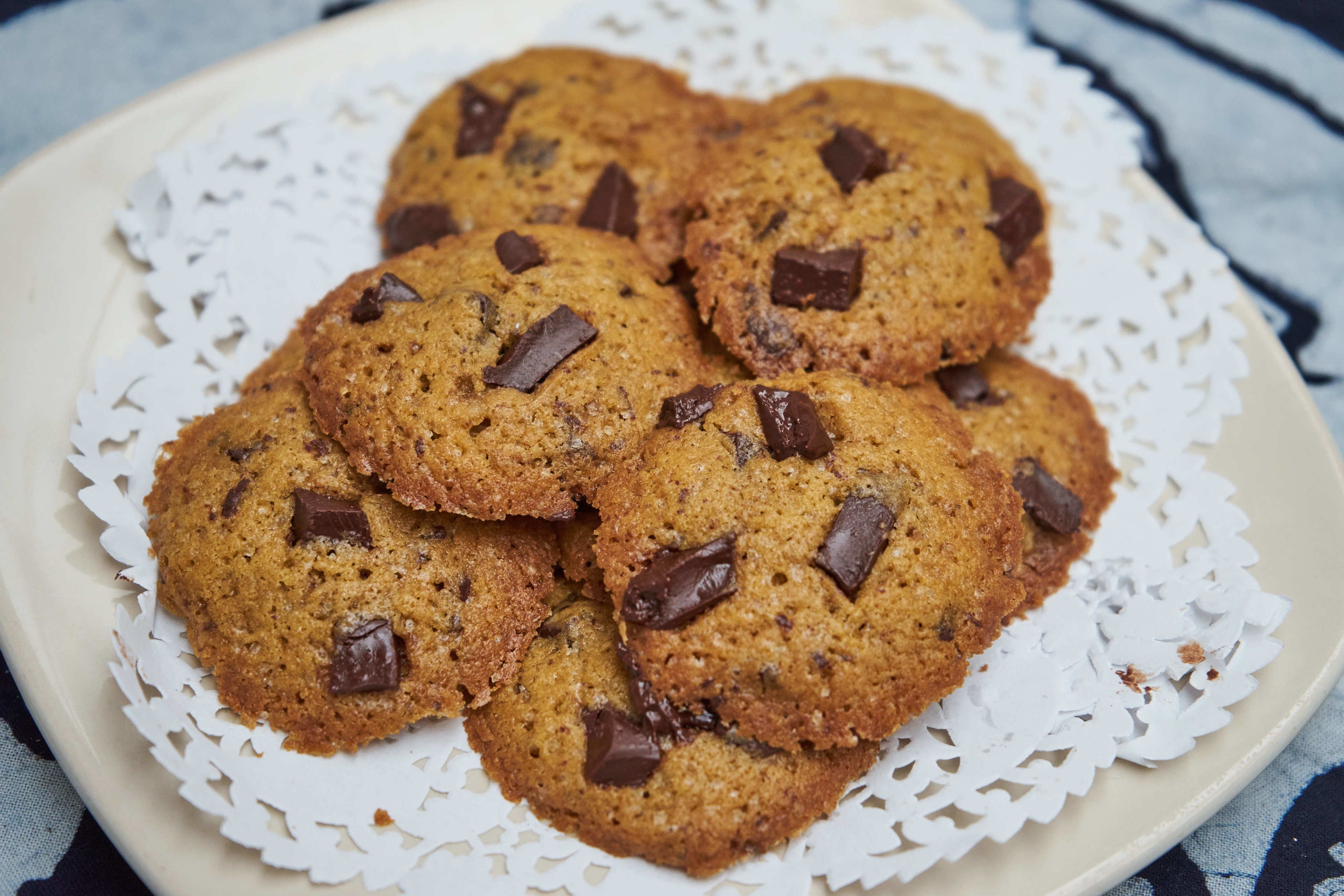 A plate of chocolate chip cookies on a white doily.