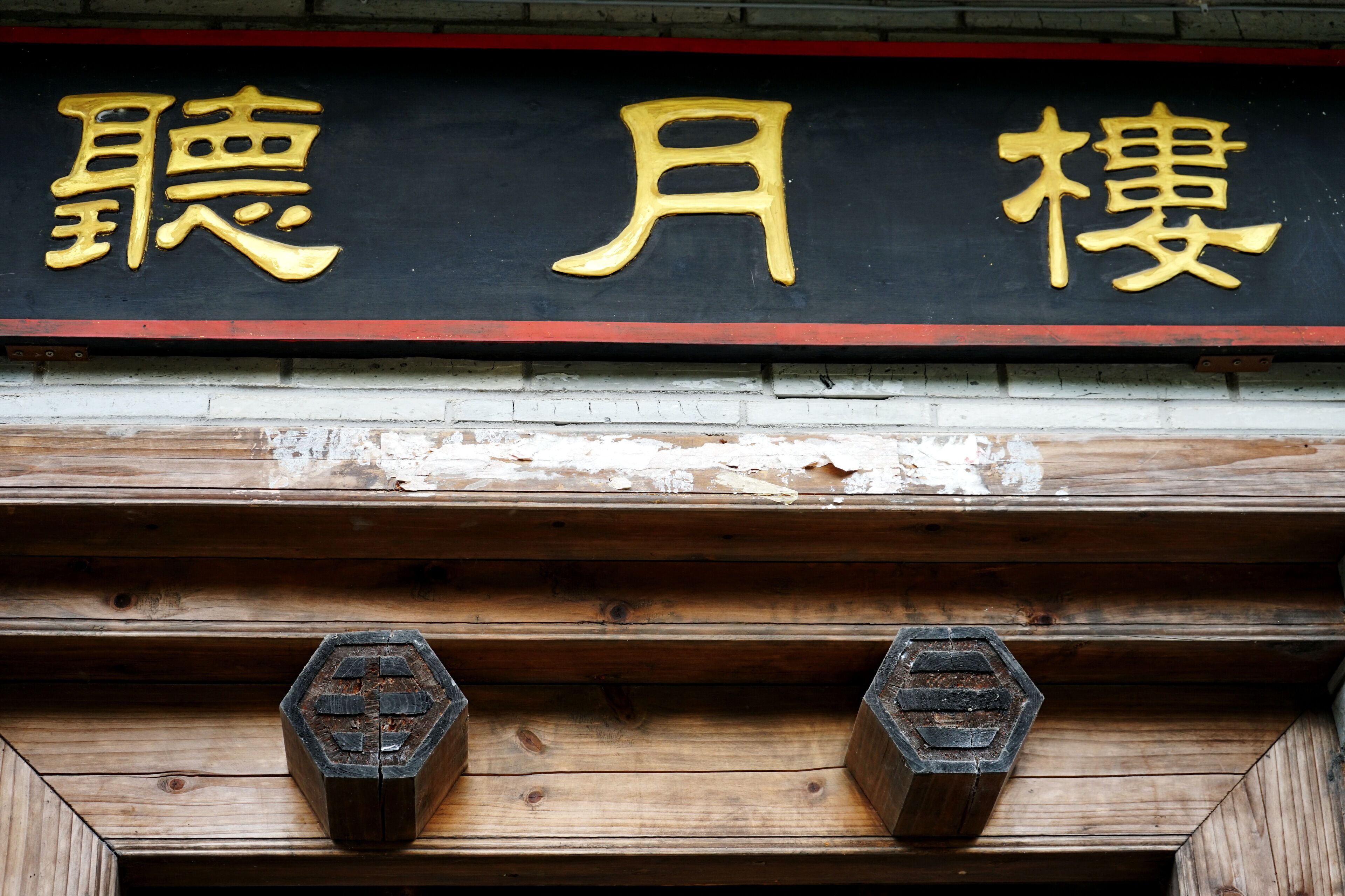 A wooden structure with a black and gold sign above it.