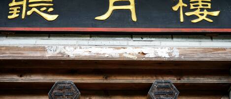 A wooden structure with a black and gold sign above it.