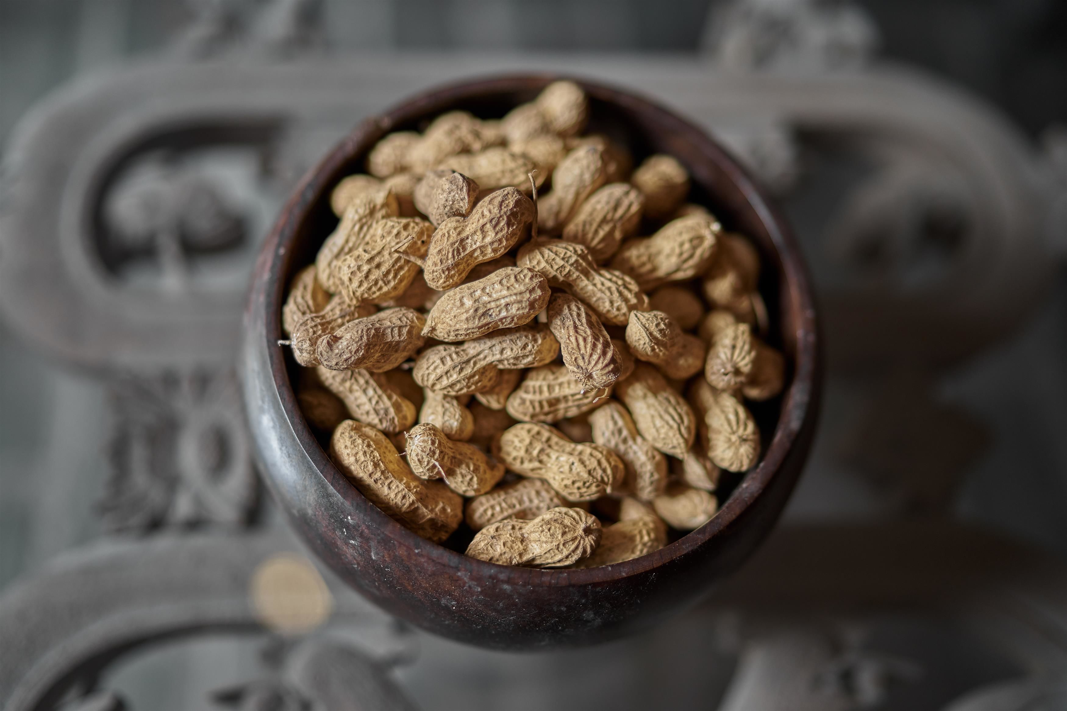 A wooden bowl filled with peanuts.