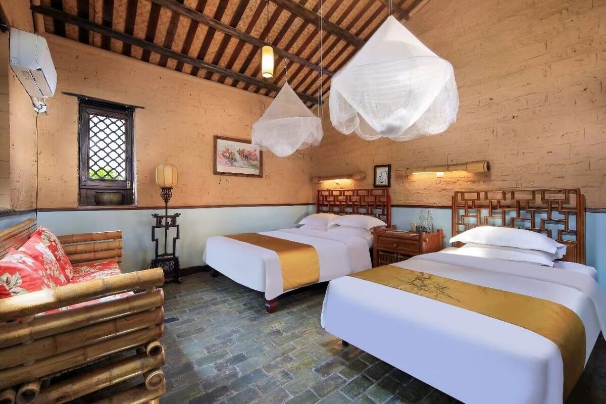 A traditional room with two beds, a wooden bench, and a window with a lattice design.