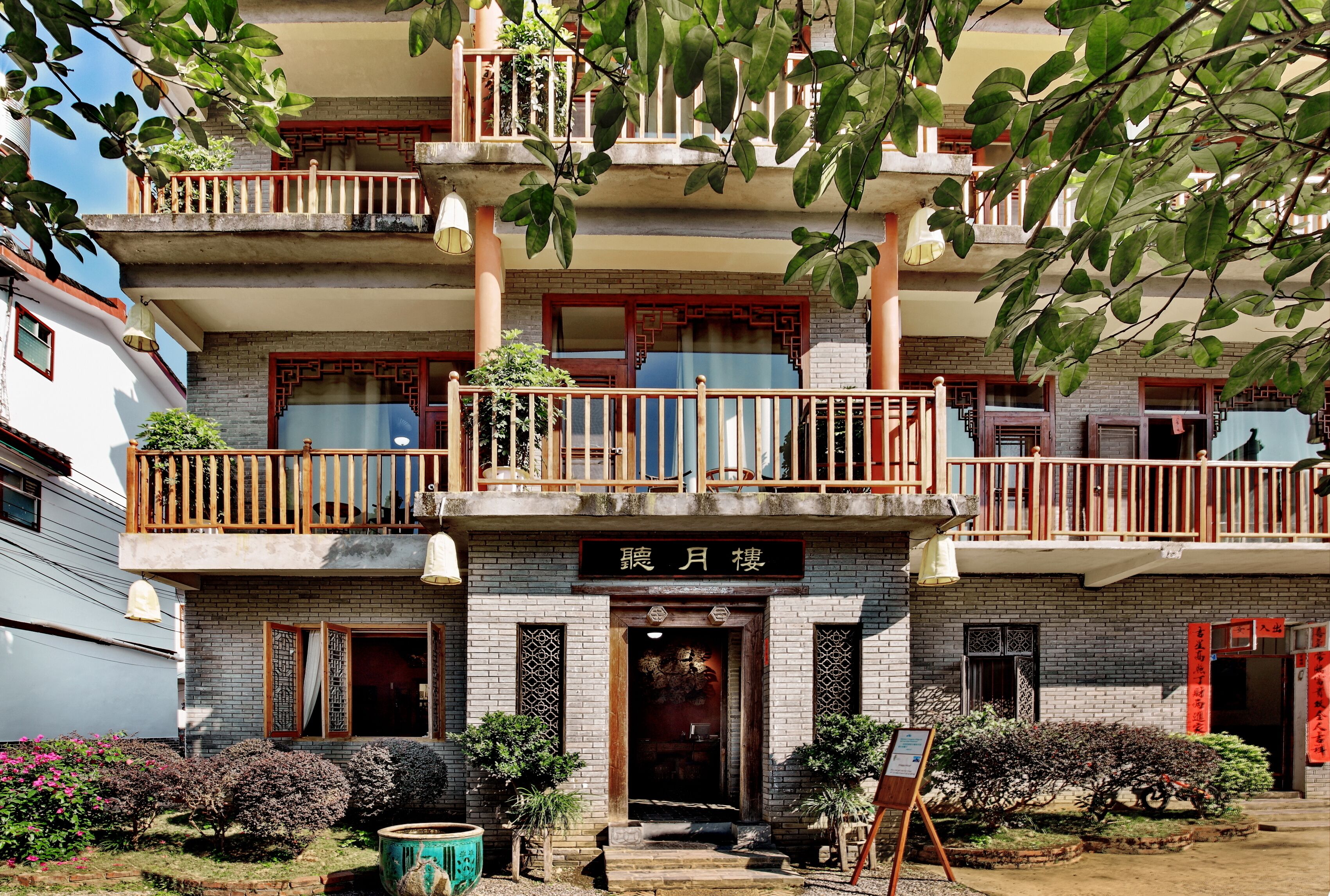 A multi-story building with a traditional architectural style, featuring balconies, a central entrance with decorative elements, and a sign above the entrance.