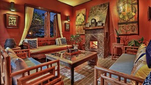Una habitación tradicional con un banco de madera bajo, una chimenea y obras de arte en las paredes.